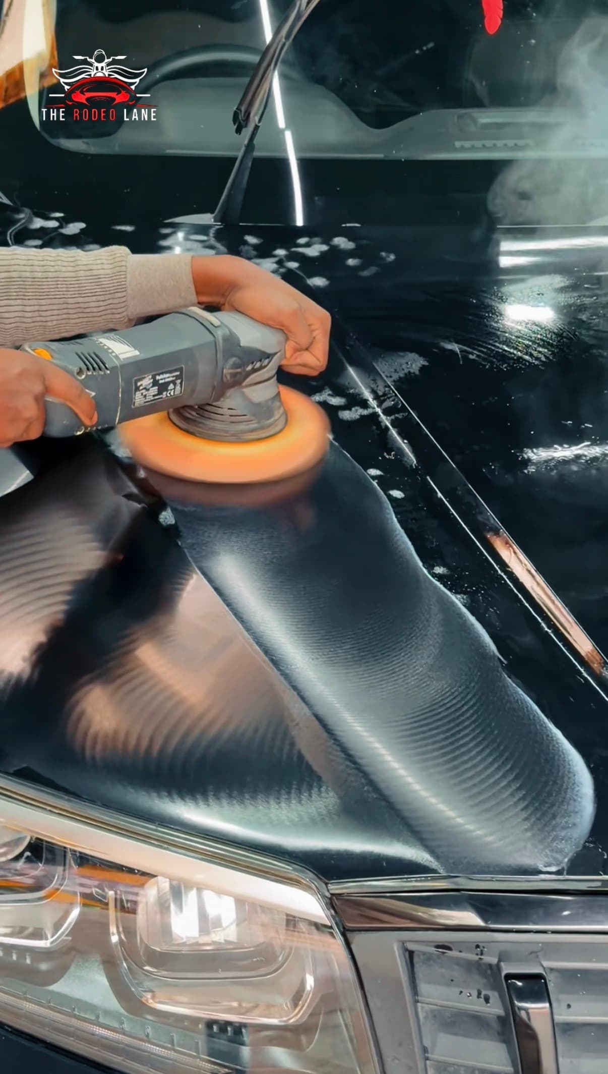 Machine polishing a glossy black vehicle panel