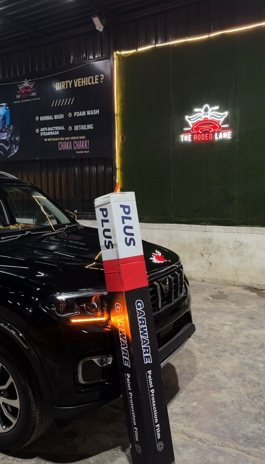 Premium paint protection film rolls beside a black car